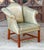 A fine English wingback library lounge armchair - upholstered in patinated green leather on a wooden frame - in the George...