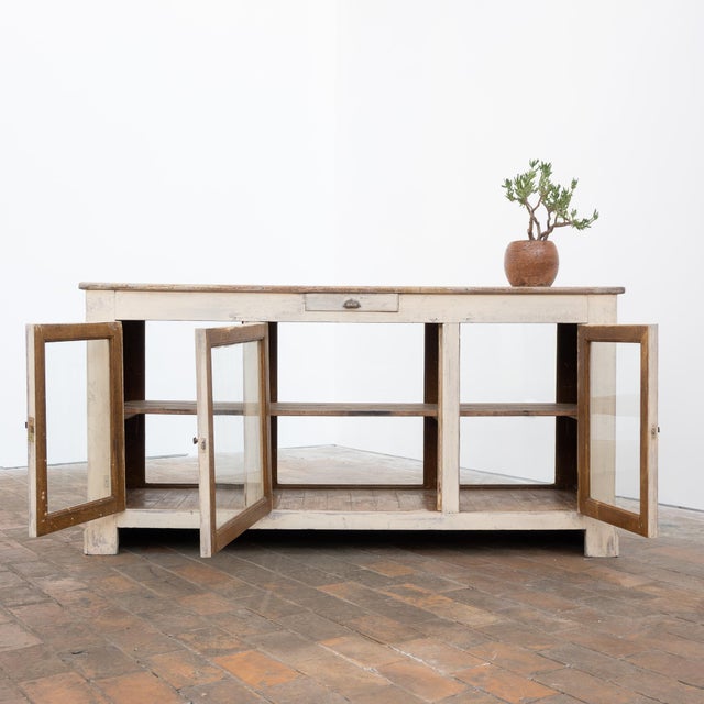 Antique painted wooden shop counter with a beautiful light, natural patina. It opens with four glass doors and has a long...