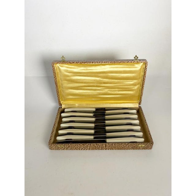 Elegant set of twelve vintage table knives featuring stainless steel blades and cream-colored Bakelite handles. Presented...