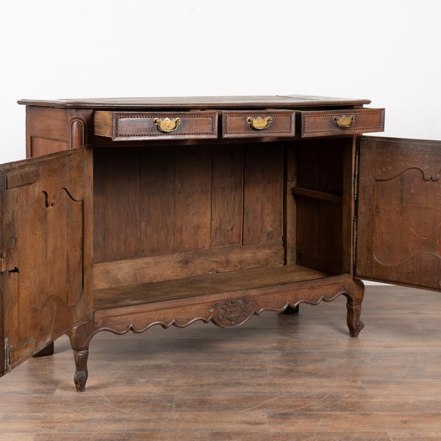 19th-century French oak sideboard buffet showcasing a deep, dark patina developed over generations of use. The façade...