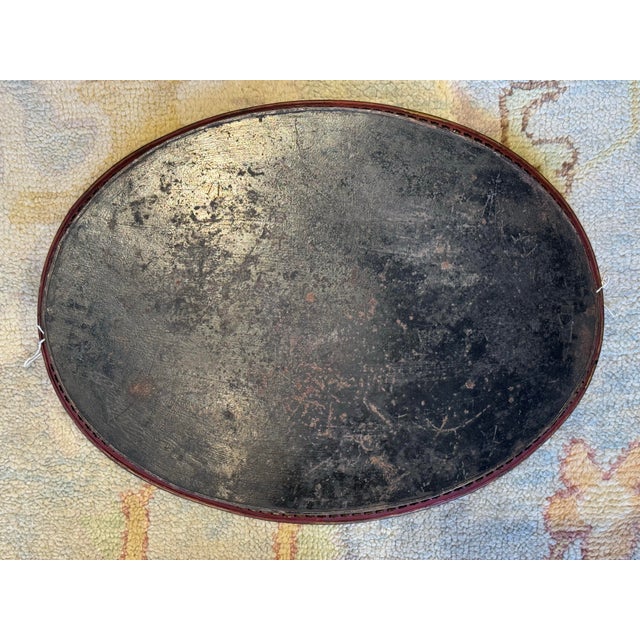 This is an antique oval toleware tray. It depicts roses and peonies. It has holes around the trim. It has handles on each...