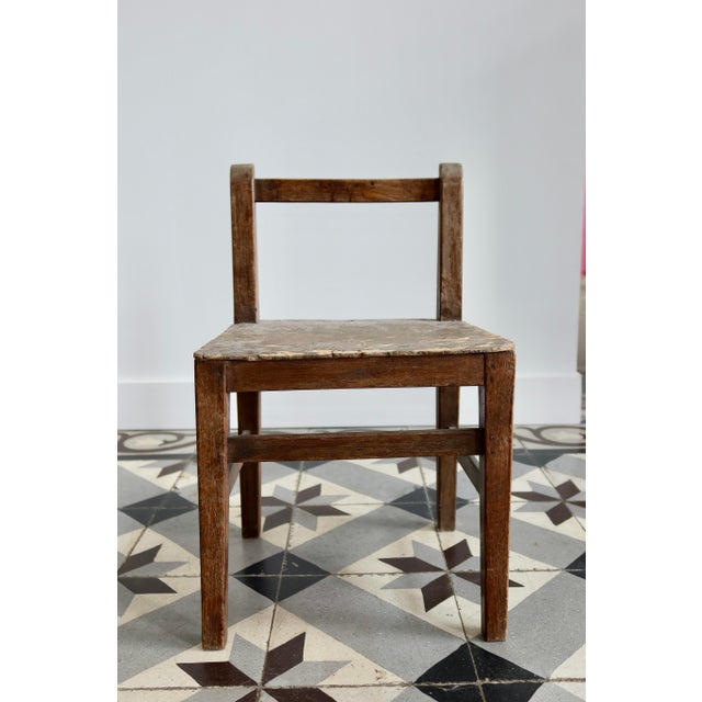 Antique wooden child's chair with a very simple, rustic design, featuring an openwork back and a straight seat. A charming...
