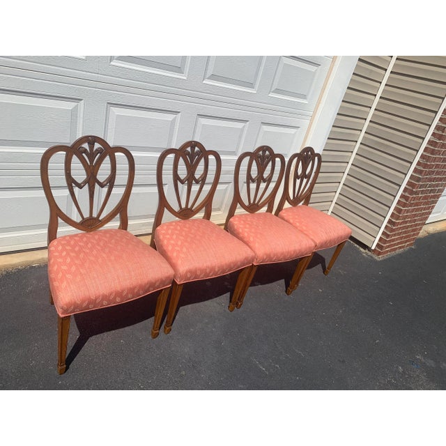 This refined set of four Hepplewhite-style dining chairs features elegant shield-shaped backs with delicately carved...