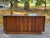 Mid-century modern credenza featuring richly figured wood grain, architectural vertical detailing, and a warm walnut-toned...