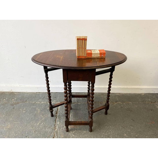 Edwardian English gate Leg table. The bevelled edge table top has two drop down leaves with barely twist gate legs which...