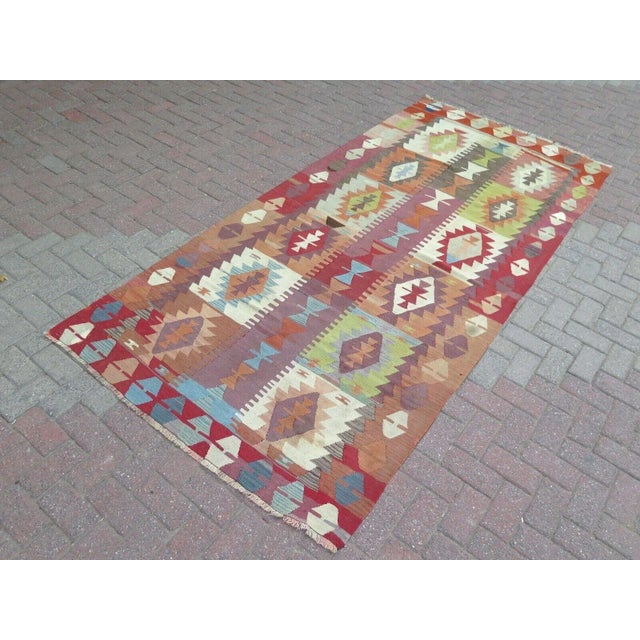 This beautiful, traditional vintage, flatweaved Turkish kilim rug is approximately 60 years old. It is handmade of very...