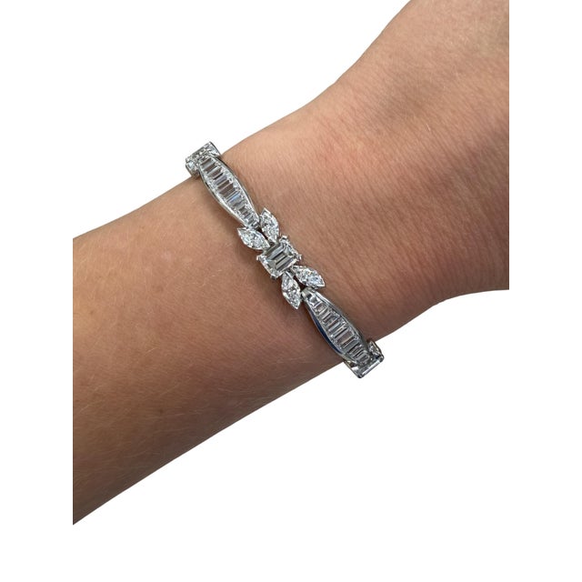 This stunning bracelet from the Mid Century era consists of five lovely Emerald cut diamonds flanked by florets of...