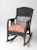 An antique wicker rocking chair featuring a sculptural armchair form and a distinctive black finish. The woven frame is...