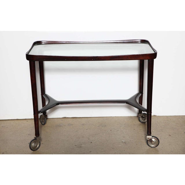 Solid Rosewood and Glass Serving Cart on four casters, Made in Italy. Featuring an open smooth sculpted rectangular...