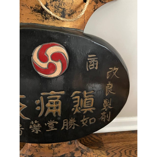 A vintage hand carved Japanese wooden apothecary trade or shop sign finished in black and gold lacquer and a red-and-white...