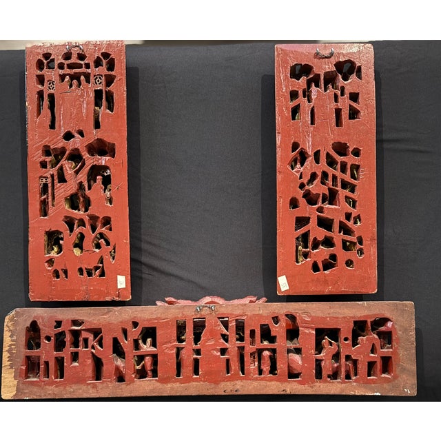 A striking set of three antique Chinese carved wood panels, deeply pierced and gilded in the traditional manner, depicting...