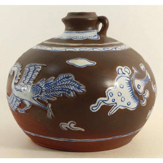 An outstanding antique vessel A brown unglazed terracotta material aka purple clay jug adorned with applied blue and white...