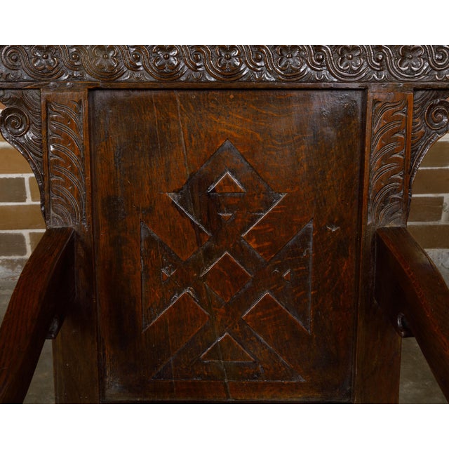 An English oak armchair from the early 18th century with carved back, downswept arms and turned legs. This exquisite...