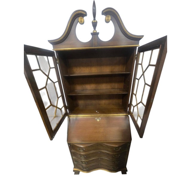 Beautiful vintage Chippendale-style secretary desk and bookcase featuring a rich dark wood finish with gold-tone accents....