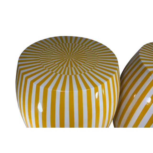 Matching pair of barrel-form resin stools with yellow and white vertical striping and coordinating radiating starburst...