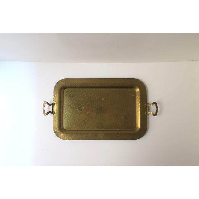 A vintage rectangular brass tray with cut‑out handles and a round stamped decorative surface, Regency / Mid‑Century Modern...