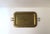 A vintage rectangular brass tray with cut‑out handles and a round stamped decorative surface, Regency / Mid‑Century Modern...