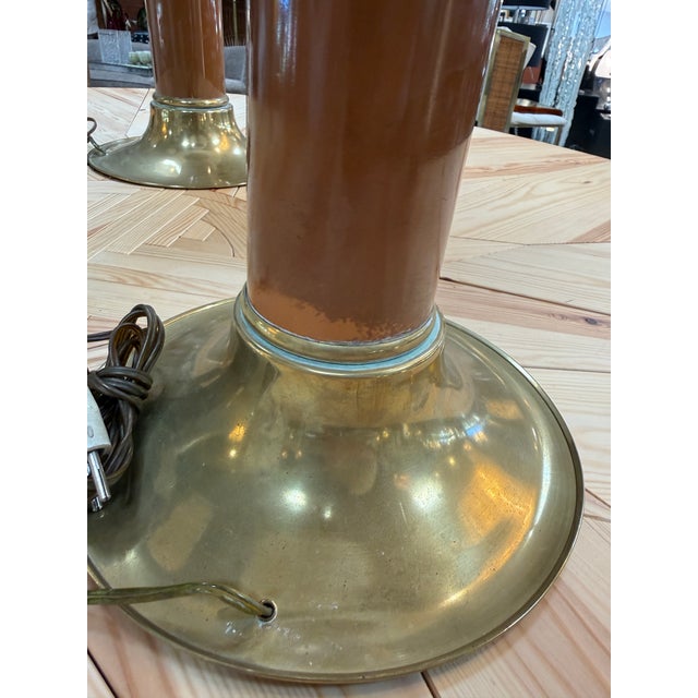 Elegant pair of mid-century modern table lamps featuring warm brass construction accented with rich brown lacquered...