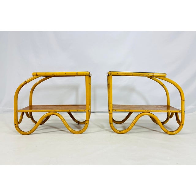 A charming pair of Mid-Century Modern side tables crafted from bent bamboo with inset glass tops and lower wood shelves....