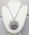 1960s rhodium plated round domed honeycomb center with ruffled "burst" surround pendant on a chain with hatched detail...