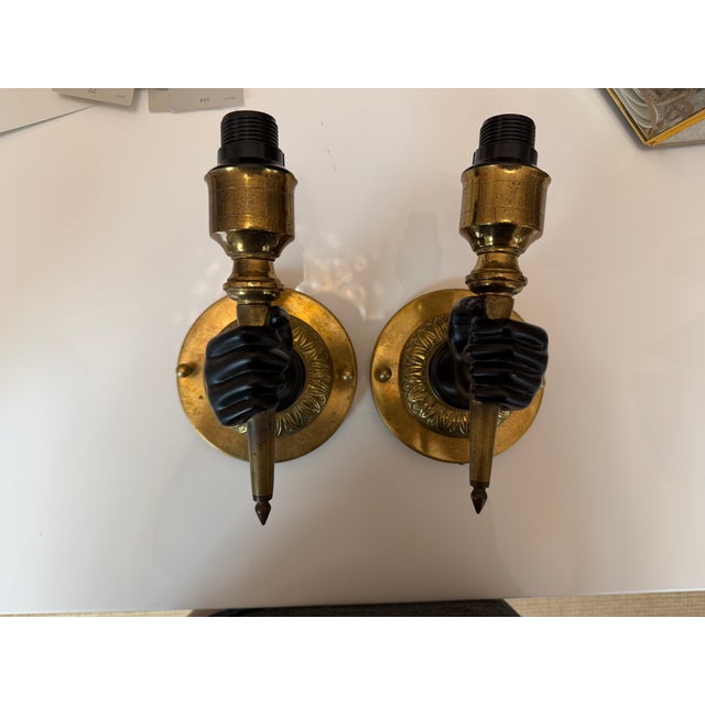 Matching pair of Maison Charles French wall sconces from the 1930s, each hand formed as a fist holding a torch, in solid...