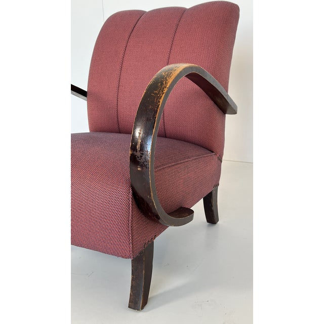 Comfortable club chair with curved armrests made of lacquered wood. The understated design stylishly complements a modern...