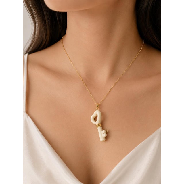This modern 14K yellow gold necklace features a white agate key pendant slide, offering a stylish and symbolic design. A...