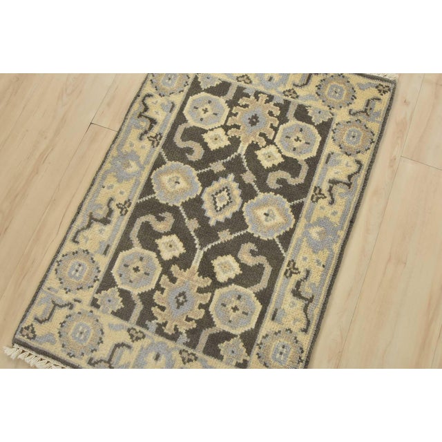 A traditional Oushak rug hand-knotted with an all-wool pile on a cotton foundation. This oriental rug features an all-over...