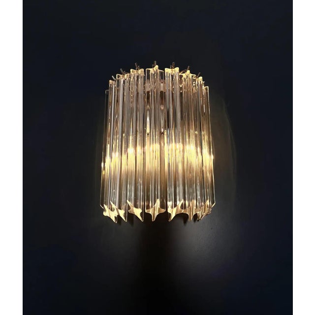An elegant and highly decorative set of four Venini Italian Murano glass and brass wall sconces, executed in the refined...