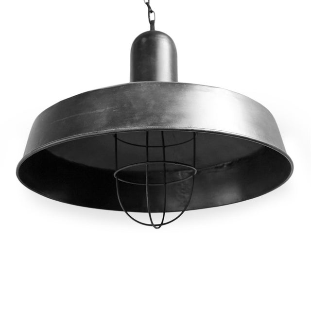 Oversized iron pendant light with clean, architectural silhouette and deep gunmetal finish. Protective wire cage...