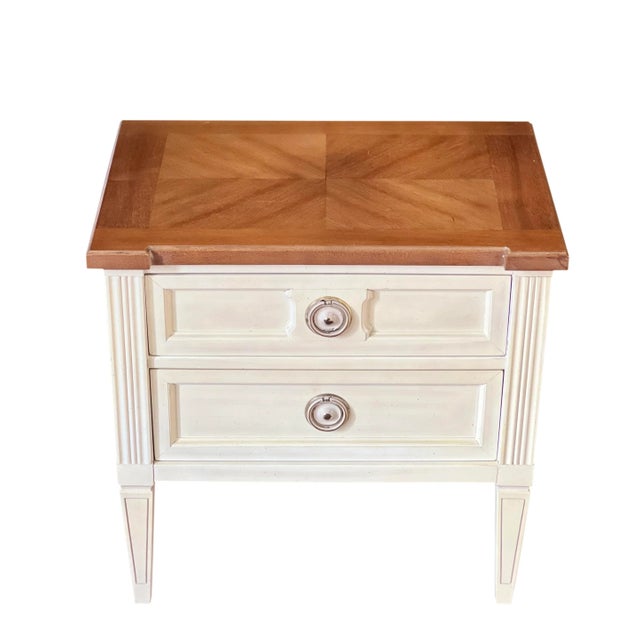 Pair of American of Martinsville Italian style nightstands. The stands are in original creamy white with a woodgrain...