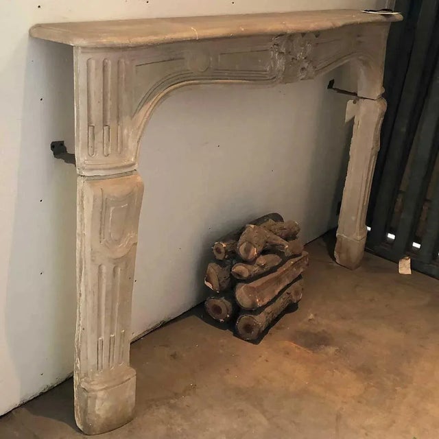 DETAILS This antique, French fireplace is carved with a shaped, overhanging mantel surmounting an ogee frieze with a...