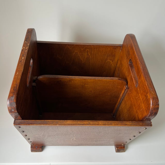 This magazine rack features a robust, hand-crafted aesthetic typical of mid-century utilitarian design. The deep-stained...