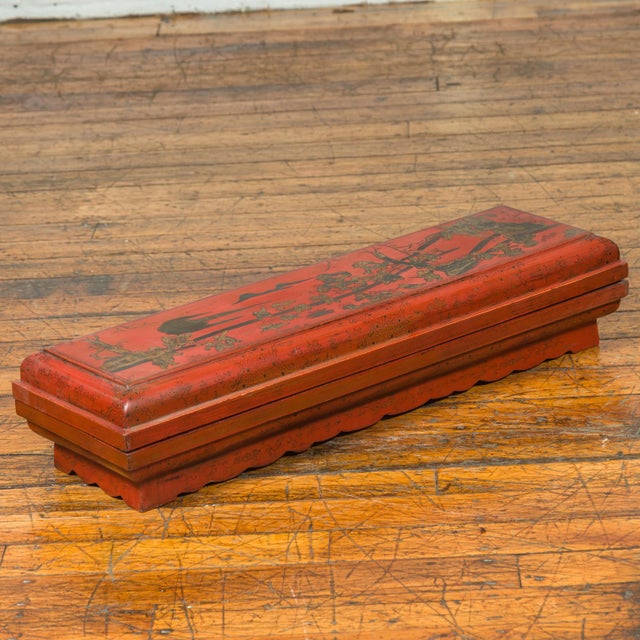 A Chinese Qing dynasty red lacquered lidded scroll box from the 19th century with distressed gold chinoiserie motifs....