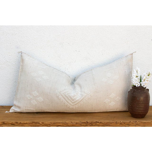 A central diamond medallion, stitched in tone-on-tone white, anchors this handcrafted Moroccan cactus silk lumbar pillow —...
