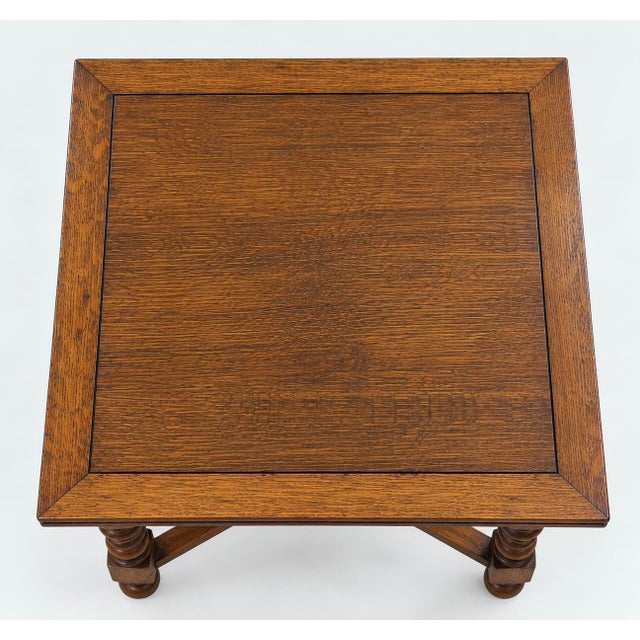 An early 20th-century Jacobean Revival oak draw-leaf table, circa 1920s, featuring a beautifully grained 36-inch square...