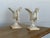 This cast iron swan figures is finished in an antique white paint and mounted on stepped socle bases with square plinths....