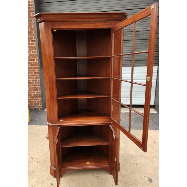 Henkel Harris corner cabinet in classic wild cherry, offering refined traditional styling and practical display storage. A...