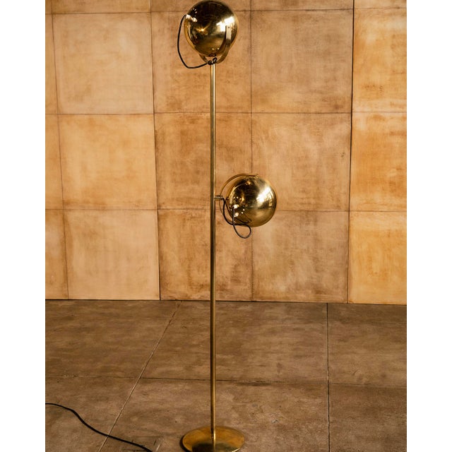 A beautifully restrained Italian floor lamp with two sculptural eyeball shades balanced on a slender brass-finished stem....