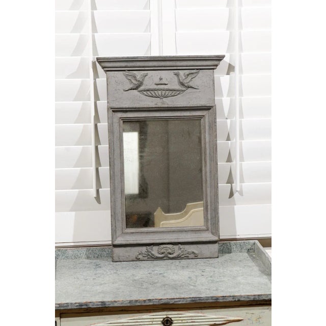 A Swedish neoclassical style painted and carved wooden mirror from the 19th century, with doves on an urn motif. Created...