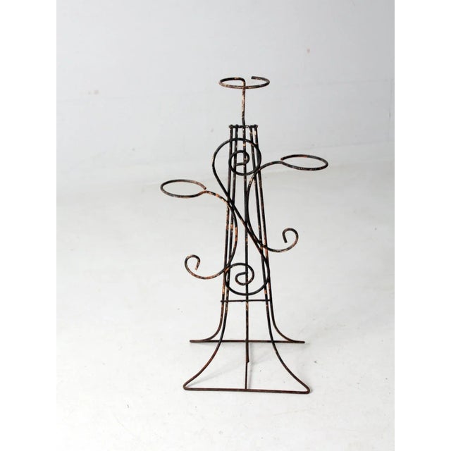 This is a mid 20th century vintage wrought iron plant stand. The tiered black iron stand has a scroll design and holds...