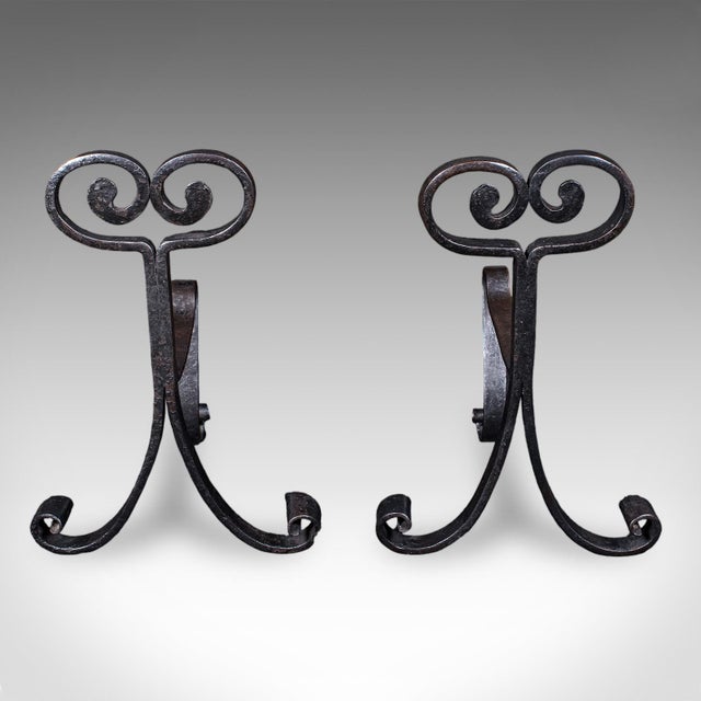 This is a pair of antique fire tool rests. An English, wrought iron fireside andiron, dating to the Art Nouveau period,...