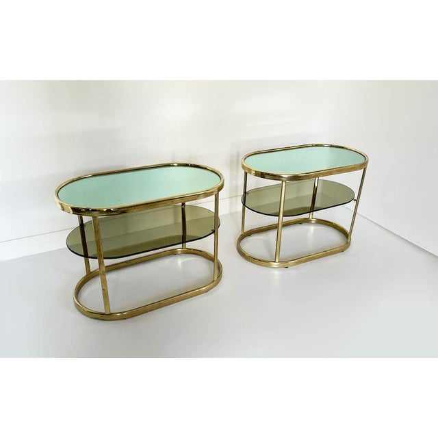 Elegant set of two 1970s-style double-shelf coffee tables or nightstands. Brass frame, smoked yellow glass center shelf,...
