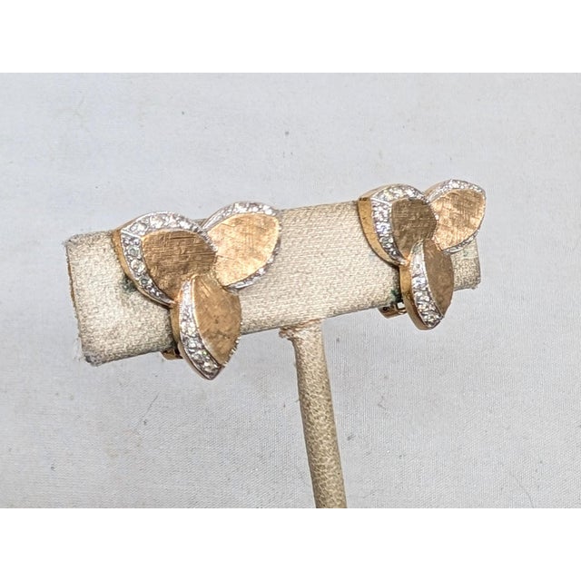 1980s textured goldtone pin wheel like 3 sections with round clear rhinestones along the edges clip earrings. Marked...