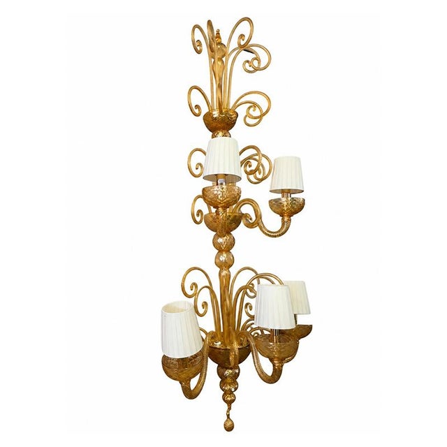 A pair of venetian wall lamps crafted from amber-colored murano glass, featuring refined craftsmanship and sinuous,...