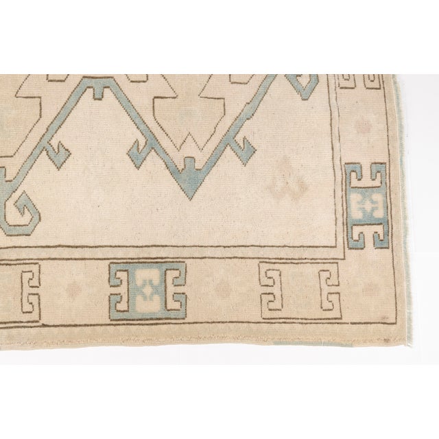 This is a vintage Turkish Oushak rug from the Mid 20th Century. The piece was hand-knotted.