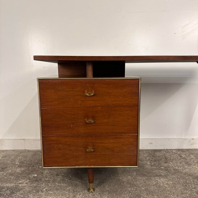 This is a mid century walnut writing desk by RWAY Furniture. This piece features a “floating” set of three drawers with a...