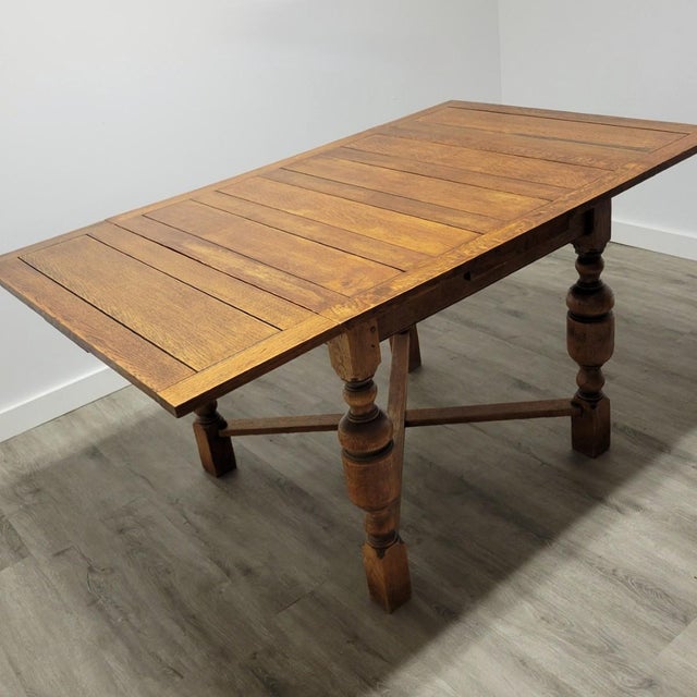 Antique English quarter-sawn oak draw-leaf dining table, circa 1920, with a paneled top, substantial baluster-turned legs...