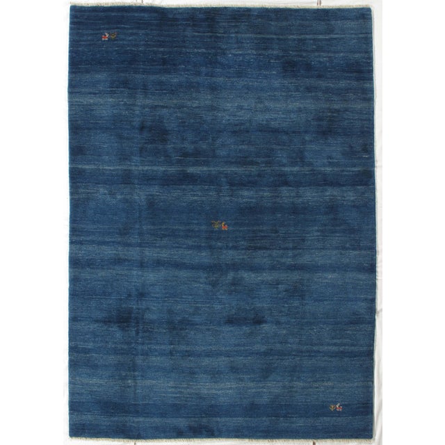 Vintage hand-knotted Persian Gabbeh rug featuring a deep blue field with subtle tonal variation and scattered small tribal...