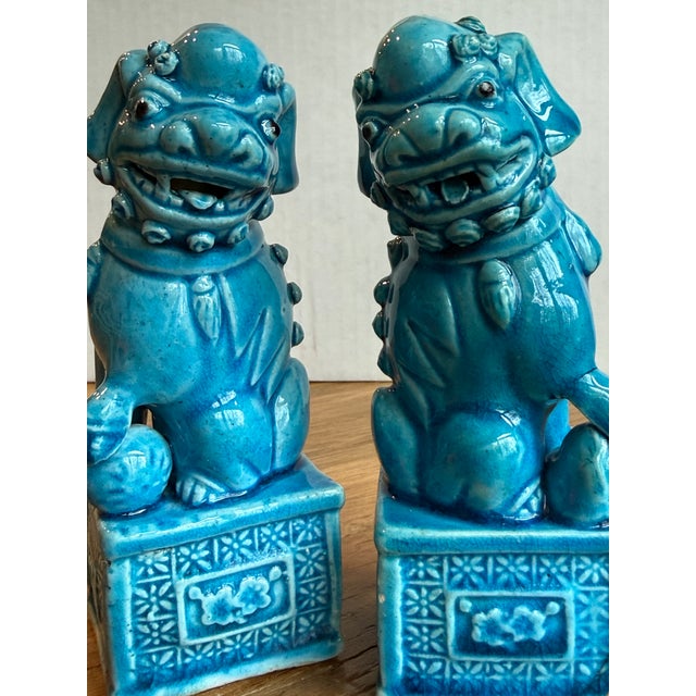 A vibrant and expressive pair of vintage turquoise-glazed foo dogs, featuring richly detailed sculpting and a striking...
